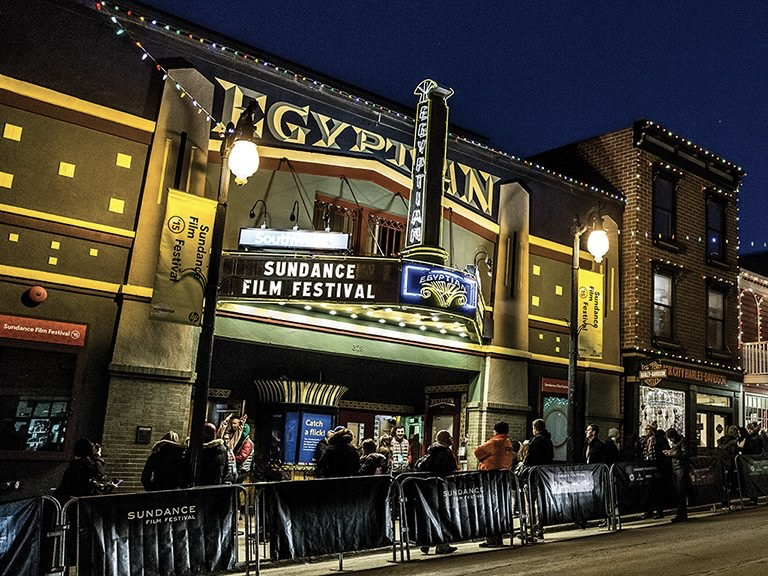 Filmmakers and festivalgoers of varied ages gathering outside a Boulder cinema on a winter evening.